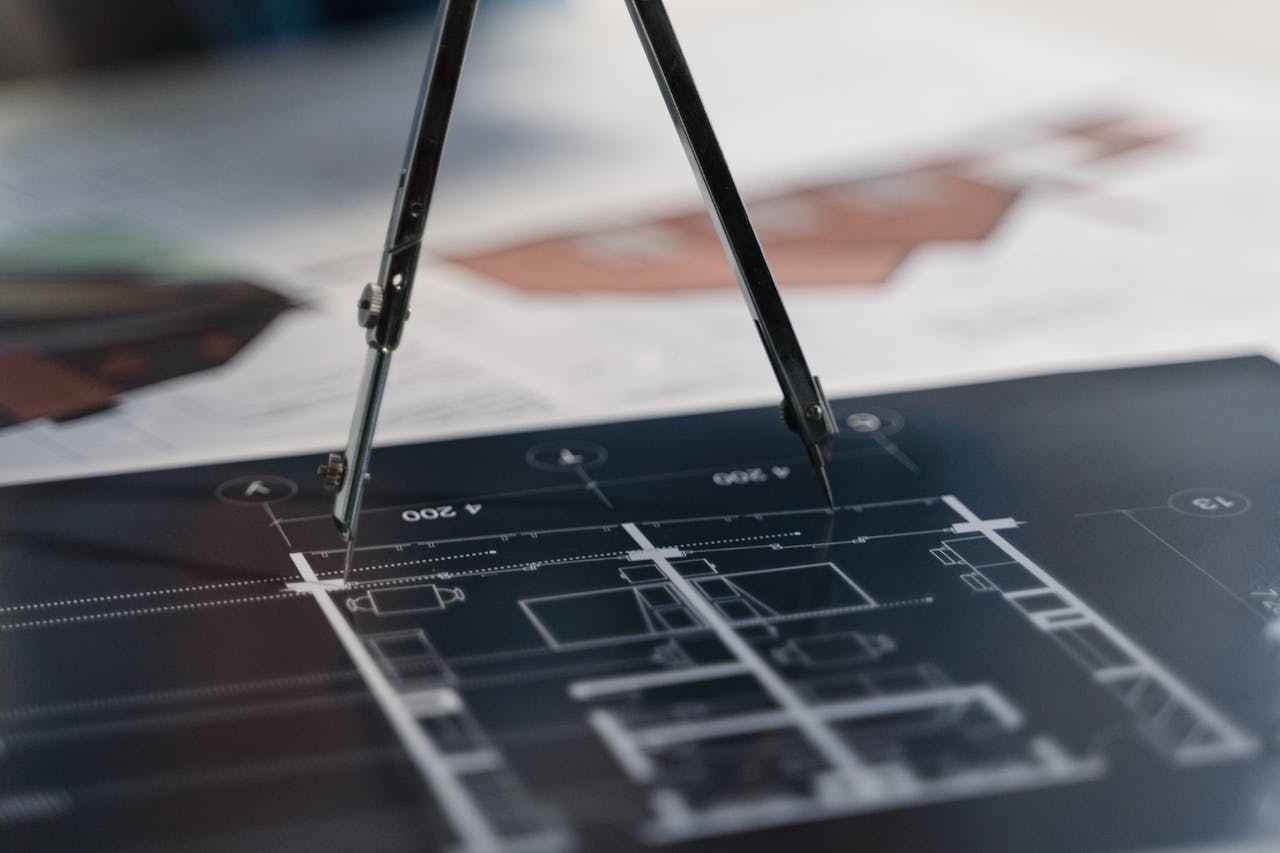 A compass on architectural blueprints, showcasing planning and measurement details.